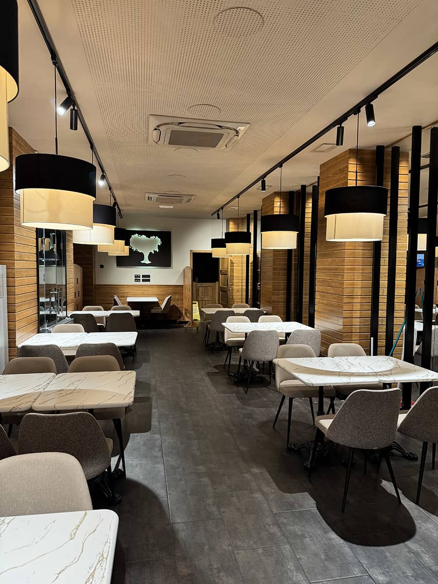 Interiorismo restaurante La Cueva de 1900 Granada con mesas de mármol y sillas tapizadas a medida.